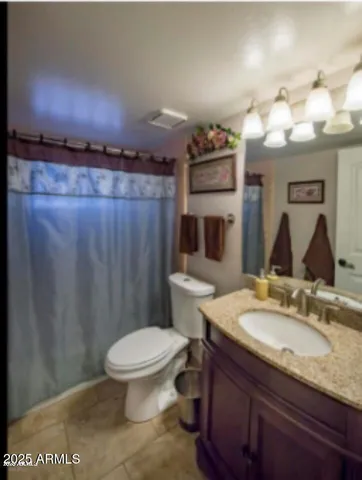 a bathroom with a granite countertop sink a toilet and a mirror
