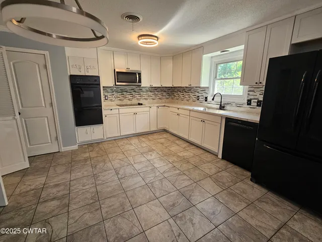 a kitchen with granite countertop a refrigerator and cabinets