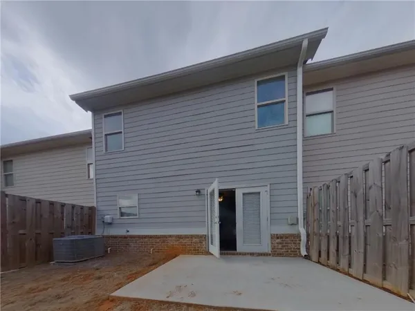 a brick house with a small yard and wooden fence