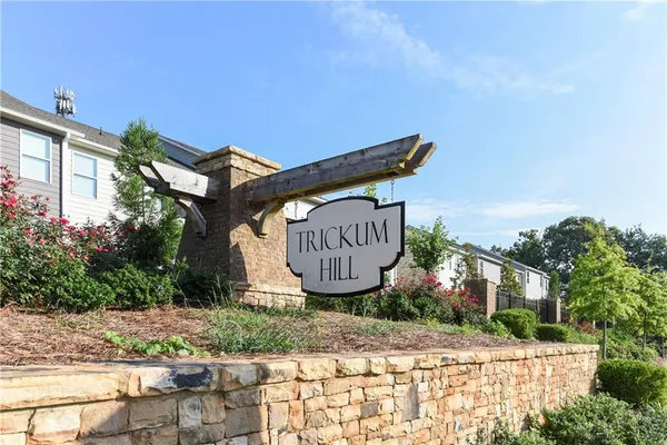 a view of a sign board with buildings in the background
