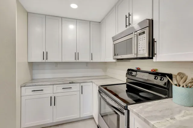 a kitchen with granite countertop white cabinets and stainless steel appliances