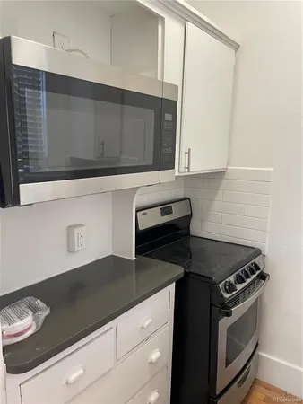 a kitchen with granite countertop white cabinets and black appliances