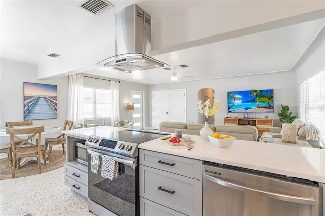 a kitchen with stainless steel appliances a sink a stove and white cabinets with wooden floor