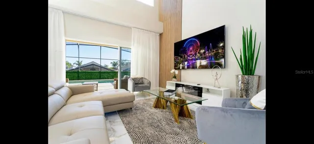 a living room with furniture a flat screen tv and a floor to ceiling window