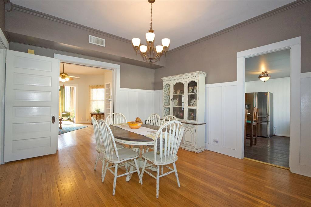 213 South Clements Street Gainesville, TX 76240 - Photo 11 of 37 a dining room with wooden floor a chandelier a glass table and chairs