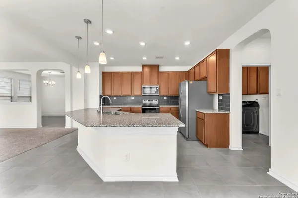 a large kitchen with stainless steel appliances kitchen island a stove a refrigerator a sink a oven and a view of living room