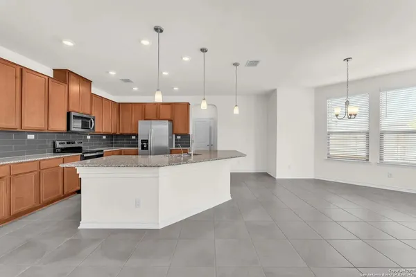 a large kitchen with stainless steel appliances kitchen island granite countertop a stove a sink a microwave and a refrigerator