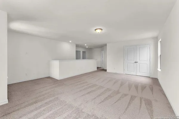 a view of an empty room with kitchen and window