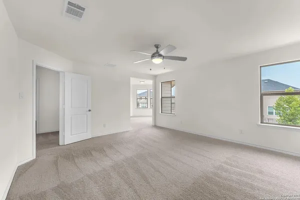 an empty room with windows and ceiling fan