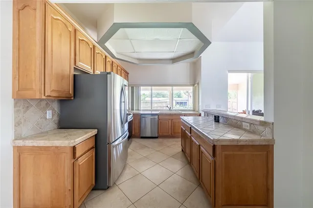 a kitchen with stainless steel appliances granite countertop a sink a stove a refrigerator a washer dryer and white cabinets