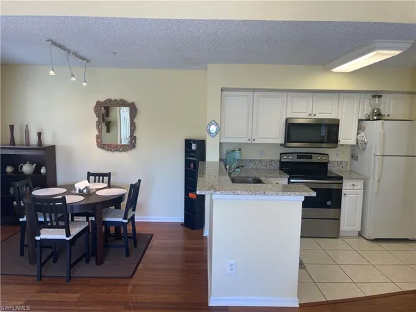 a kitchen with stainless steel appliances a dining table chairs and a refrigerator