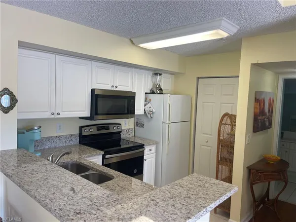 a kitchen with stainless steel appliances granite countertop a refrigerator a stove and a sink