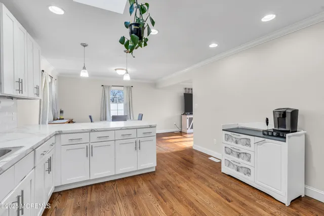 a large white kitchen with stainless steel appliances granite countertop a stove a sink dishwasher and white cabinets with wooden floor