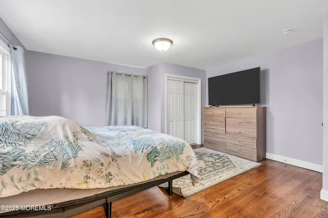 a bedroom with a bed and walk in closet with wooden floor