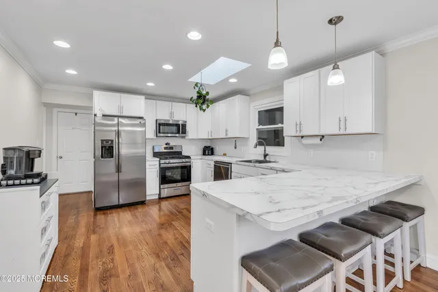 a kitchen with kitchen island a sink stainless steel appliances and wooden floor