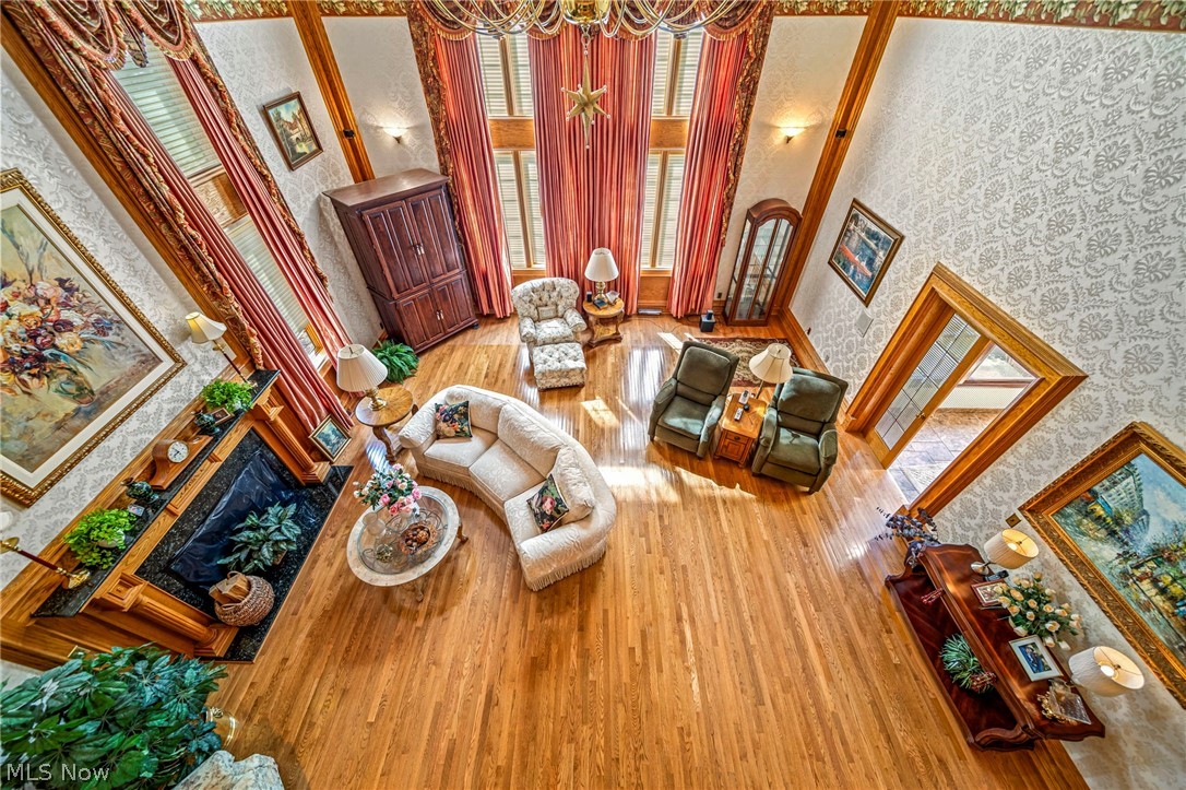 8801 Bunker Road Orwell, OH 44076 - Photo 32 of 50 Living room featuring wallpapered walls, a high ceiling, light wood-type flooring, a fireplace, and a chandelier