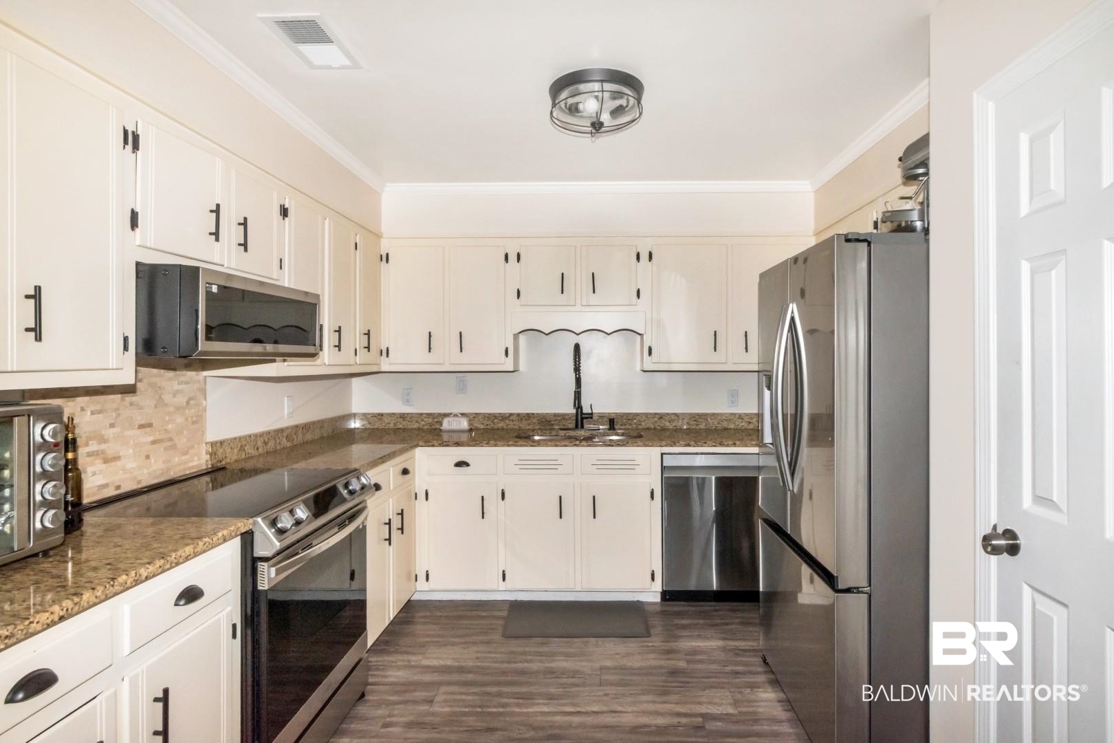 9410 Ashwood Court Mobile, AL 36695 - Photo 11 of 20 Kitchen featuring appliances with stainless steel finishes, dark stone countertops, crown molding, dark wood finished floors, and white cabinetry