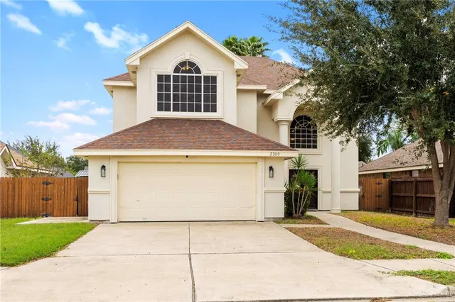 a view of a white house with a yard and large tree