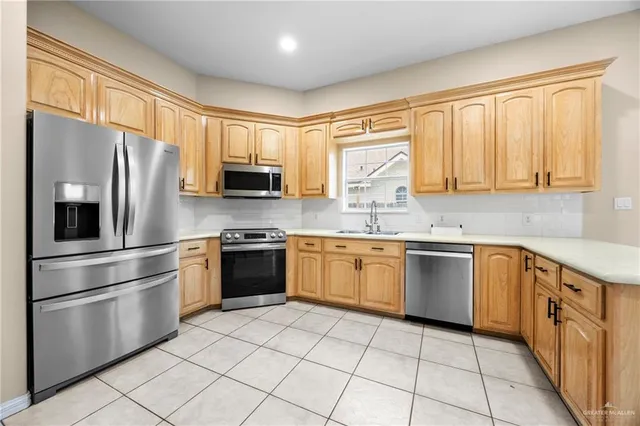 a kitchen with stainless steel appliances granite countertop a refrigerator a stove a sink and a microwave