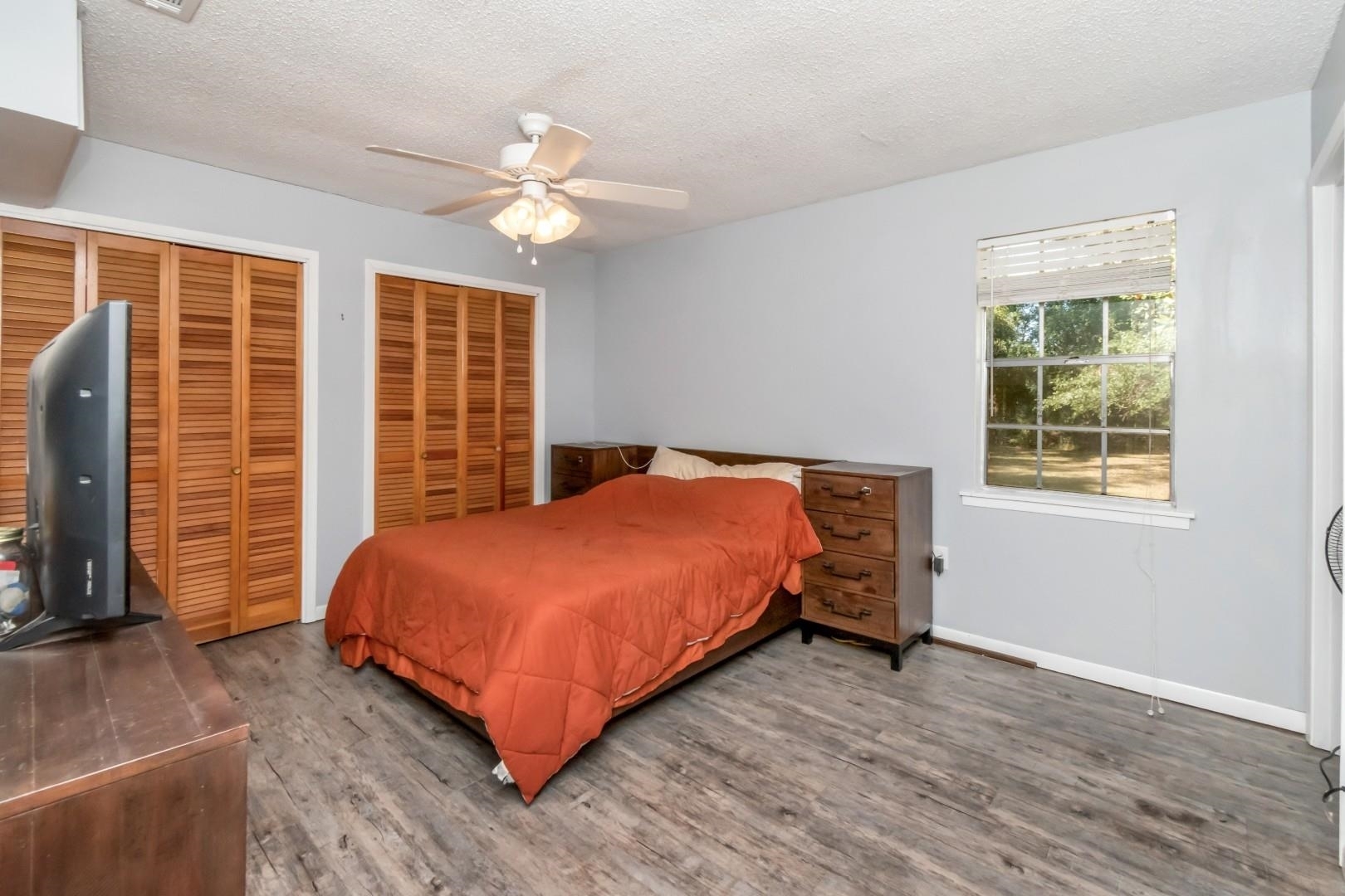 6405 1st Street Wilmer, AL 36587 - Photo 12 of 38 Bedroom featuring multiple closets, a textured ceiling, wood finished floors, and a ceiling fan