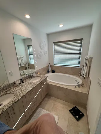 a bathroom with a granite countertop tub a sink and a large mirror