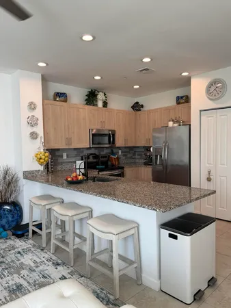 a kitchen with stainless steel appliances a stove a sink a microwave a refrigerator and chairs