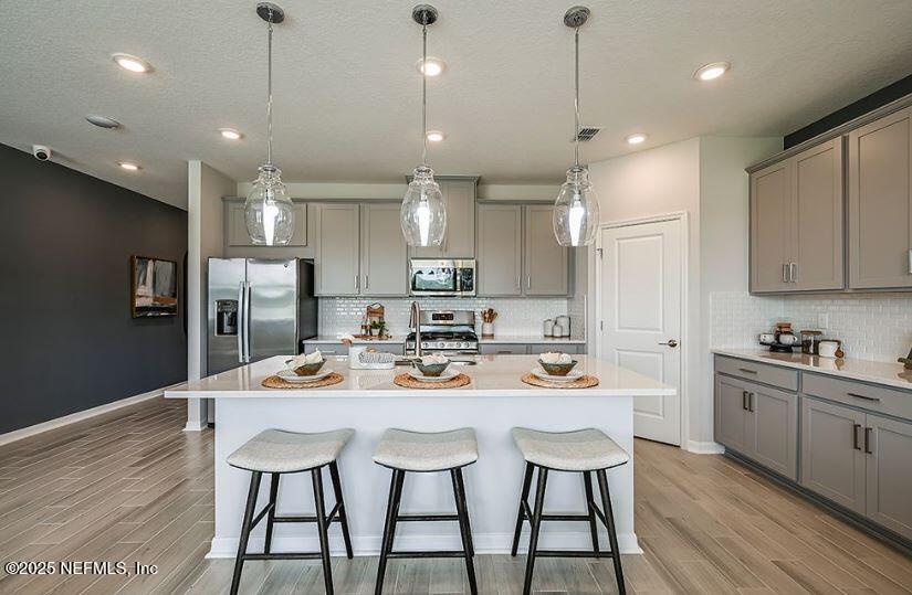 299 Cherry Elm Drive St. Augustine, FL 32092 - Photo 13 of 18 a kitchen with stainless steel appliances kitchen island granite countertop a dining table chairs refrigerator and microwave