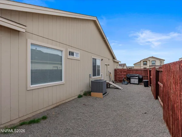 a view of a house with a barbeque and wooden fence