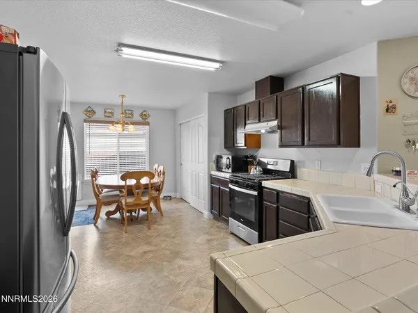a kitchen with stainless steel appliances kitchen island granite countertop a refrigerator a stove a sink a dining table and chairs with wooden floor