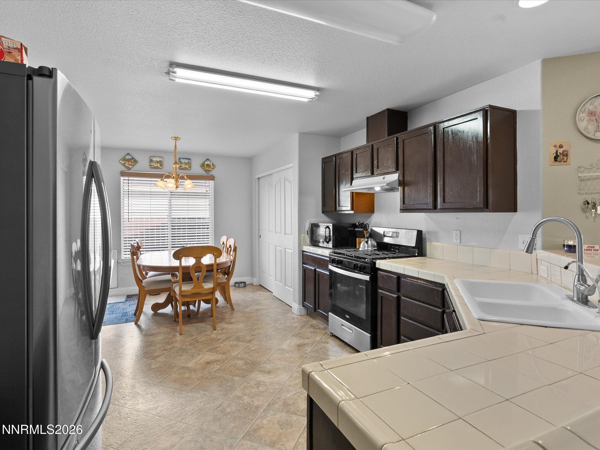 710 Keppel Street Fallon, NV 89406 - Photo 7 of 38 a kitchen with stainless steel appliances kitchen island granite countertop a refrigerator a stove a sink a dining table and chairs with wooden floor