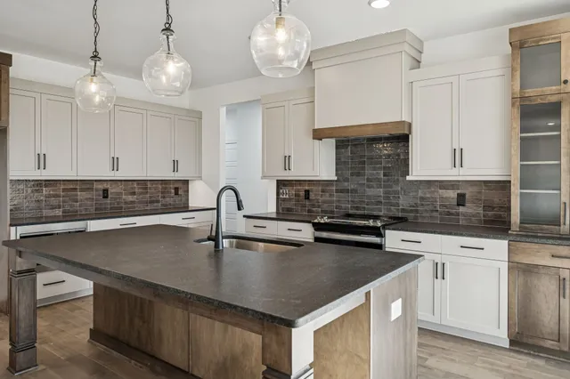a kitchen with granite countertop a sink a stove and cabinets