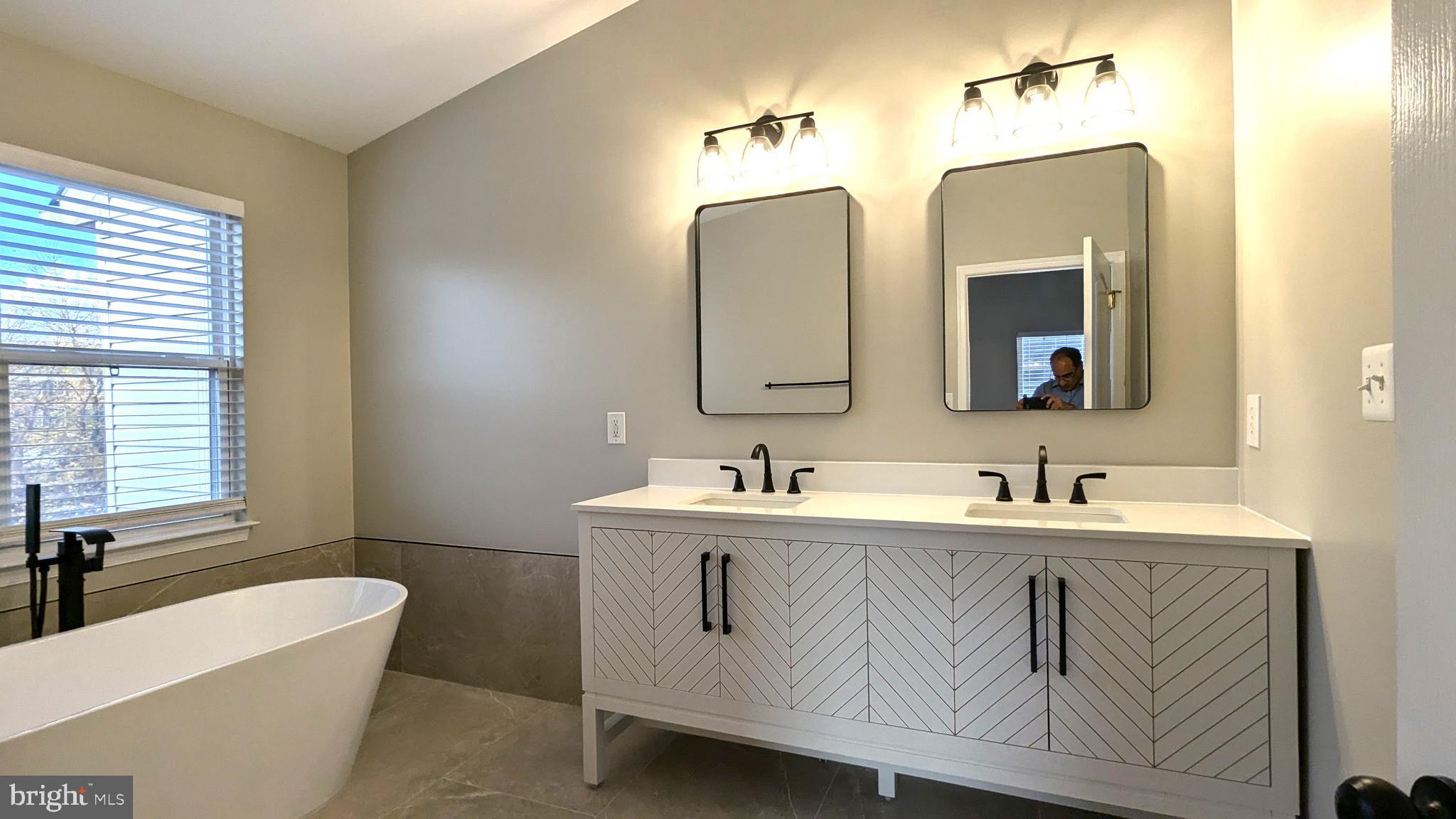 21506 Trowbridge Square Ashburn, VA 20147 - Photo 25 of 66 a bathroom with double vanity sinks a large mirror and a bathtub