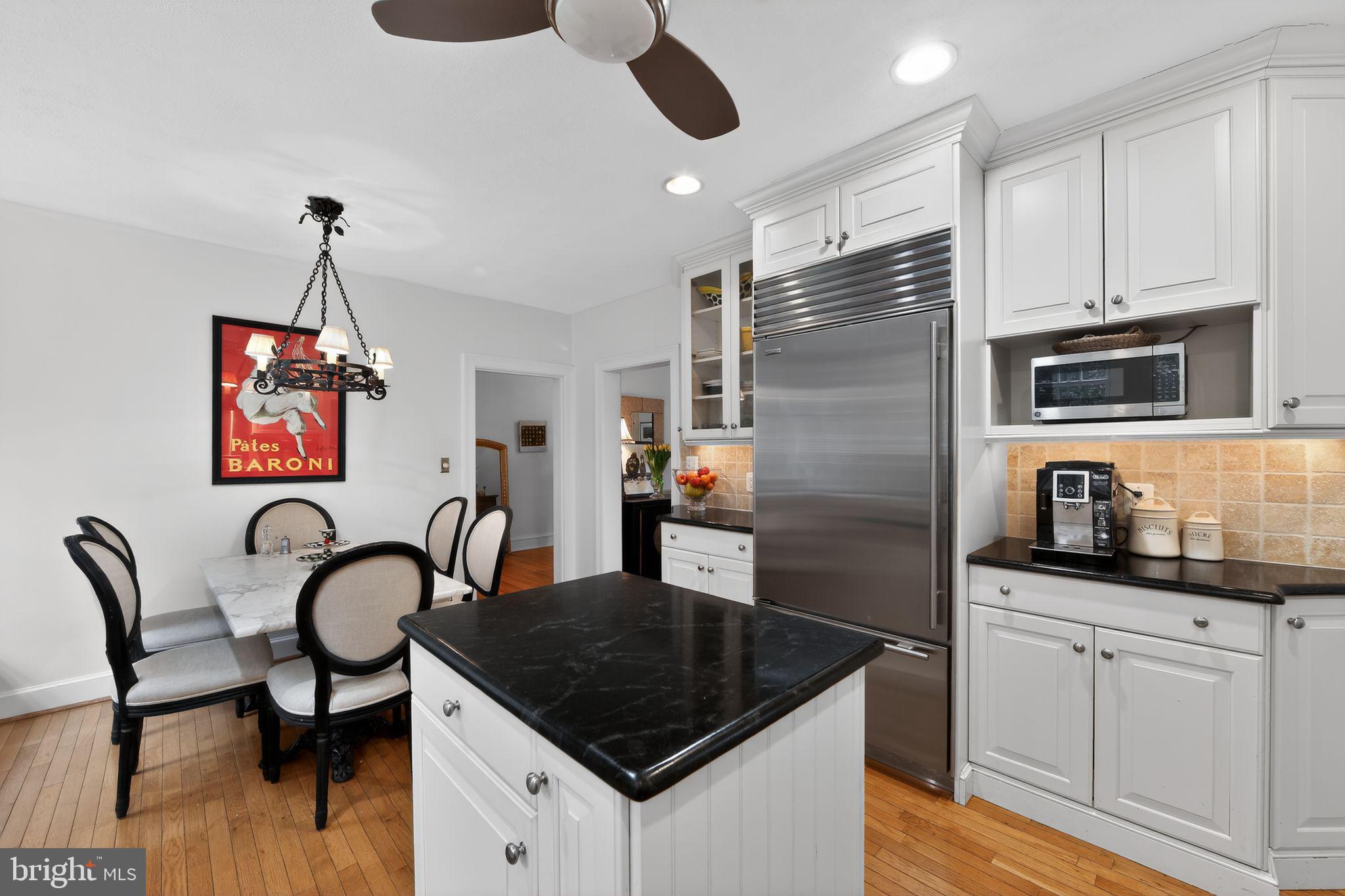306 Windsor Avenue Wayne, PA 19087 - Photo 12 of 36 a kitchen with stainless steel appliances granite countertop a stove top oven a sink a dining table and chairs with wooden floor