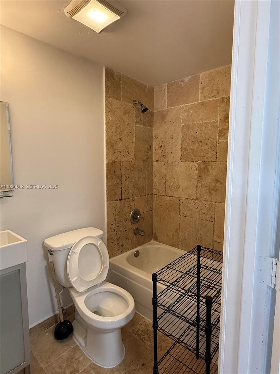 894 80th Street, Unit 1 Miami Beach, FL 33141 - Photo 7 of 13 a bathroom with a granite countertop toilet a sink and a shower