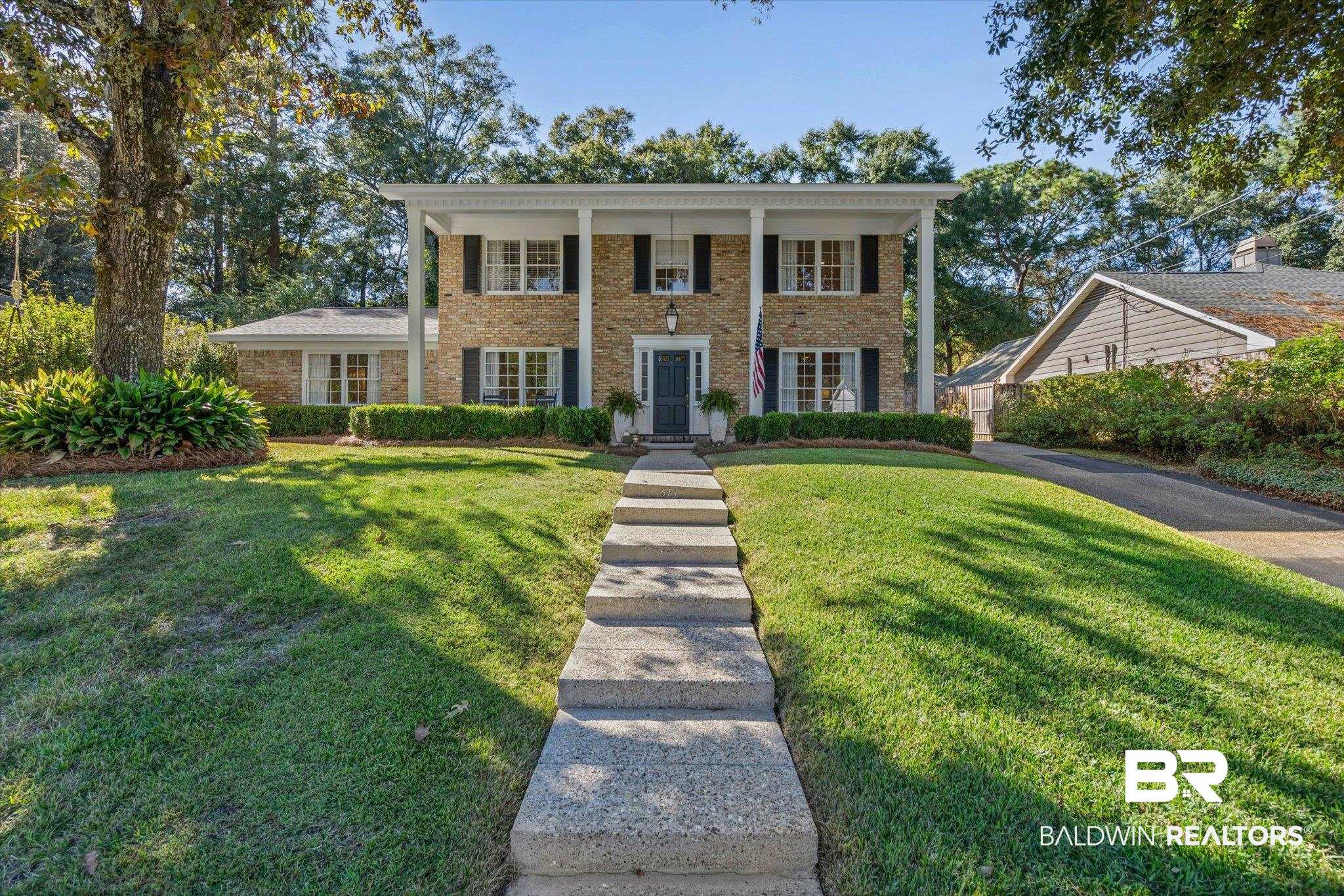 513 Spring Park Drive East Mobile, AL 36608 - Photo 1 of 44 Neoclassical / greek revival house featuring covered porch, a front lawn, and brick siding
