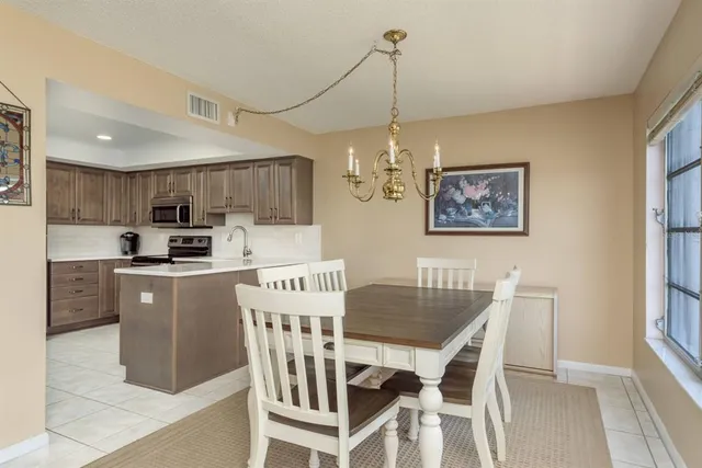 a kitchen with stainless steel appliances granite countertop a dining table chairs refrigerator and microwave