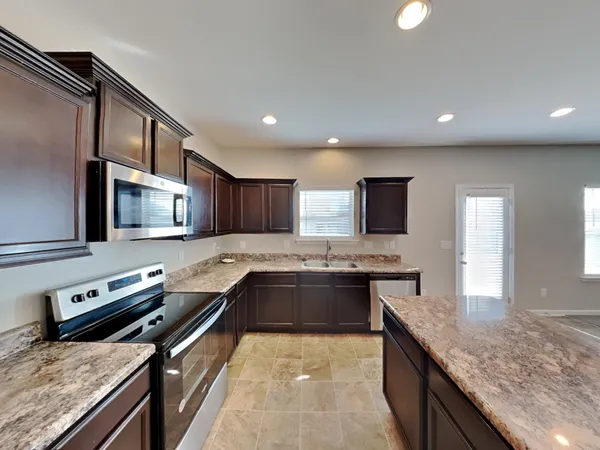 a large kitchen with stainless steel appliances granite countertop a stove top oven a sink and dishwasher