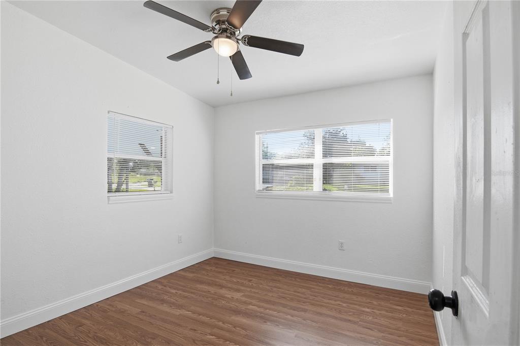 5601 Meridian Way Orlando, FL 32808 - Photo 17 of 34 an empty room with wooden floor ceiling fan and windows