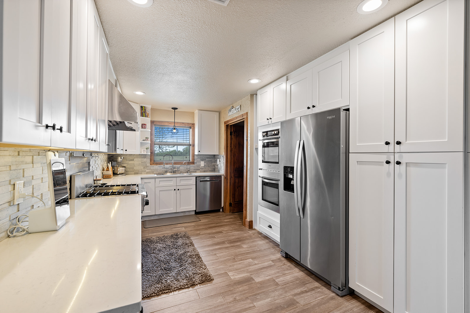 1001 Gravel Pit Road Taylor, TX 76574 - Photo 8 of 38 Kitchen with white cabinetry, stainless steel appliances, light wood-type flooring, tasteful backsplash, and a textured ceiling