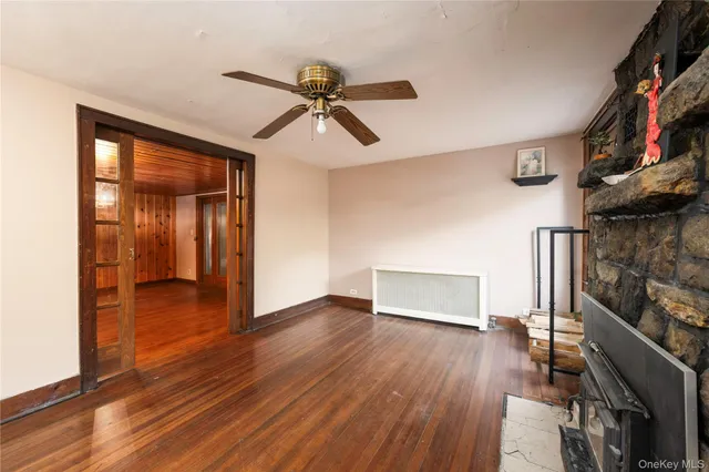 a view of empty room with wooden floor and fan