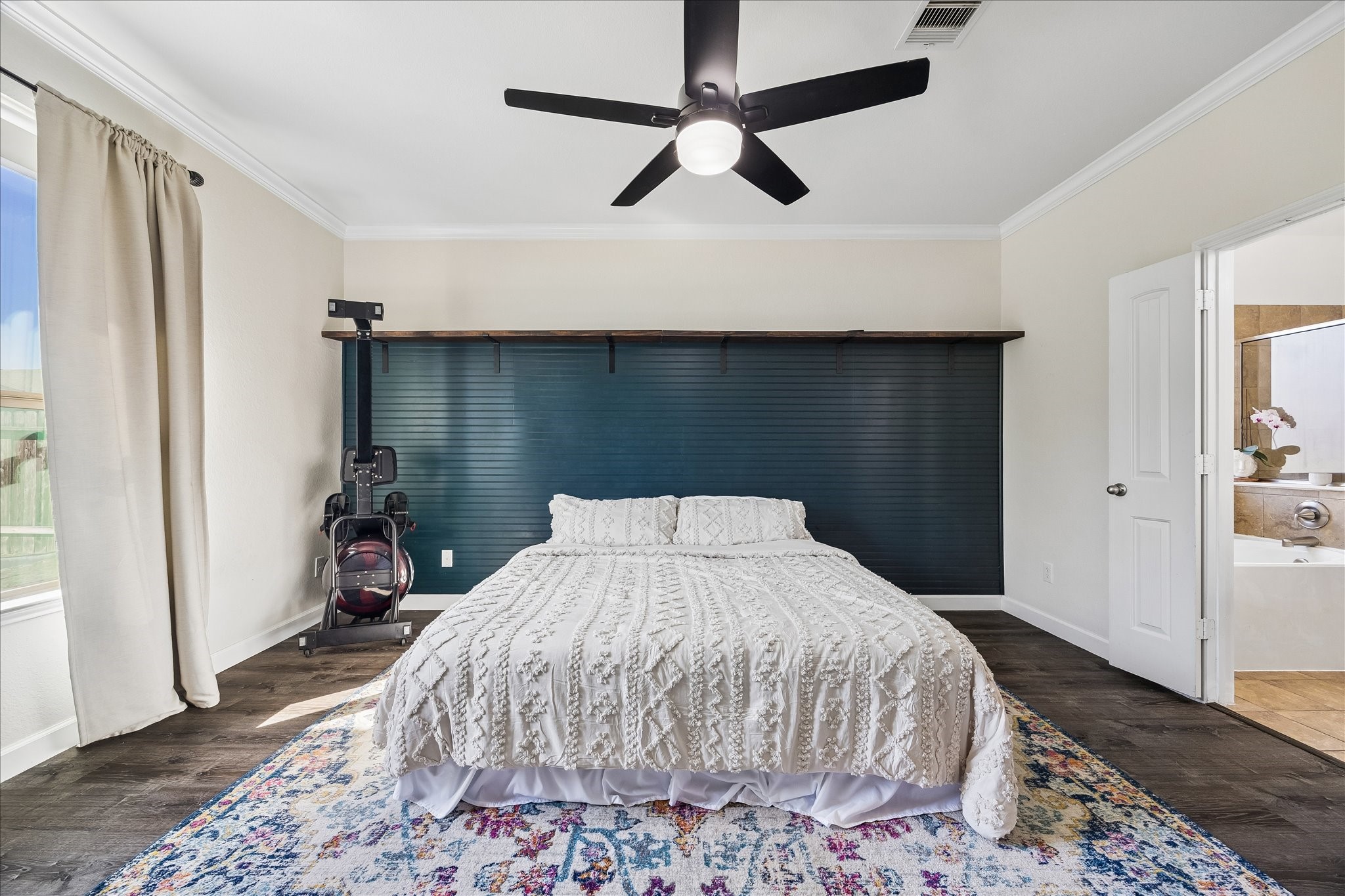 326 Ralston Ranch Court Richmond, TX 77469 - Photo 14 of 28 Bright and inviting primary bedroom centered around a statement accent wall with picture ledge, complemented by large windows for natural light, sleek ceiling fan, and seamless access to the ensuite bath.