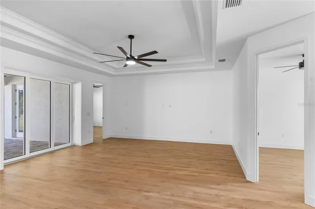 a view of an empty room with a window and wooden floor