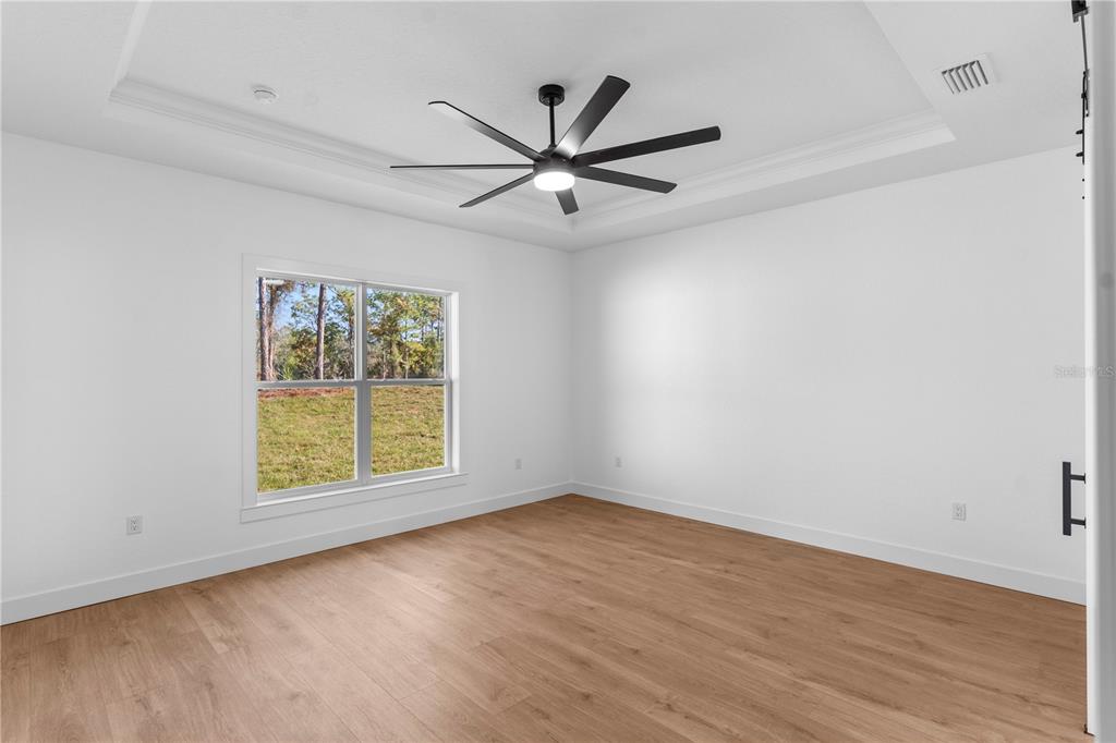 8090 Nordica Road Brooksville, FL 34613 - Photo 19 of 56 an empty room with wooden floor fan and windows