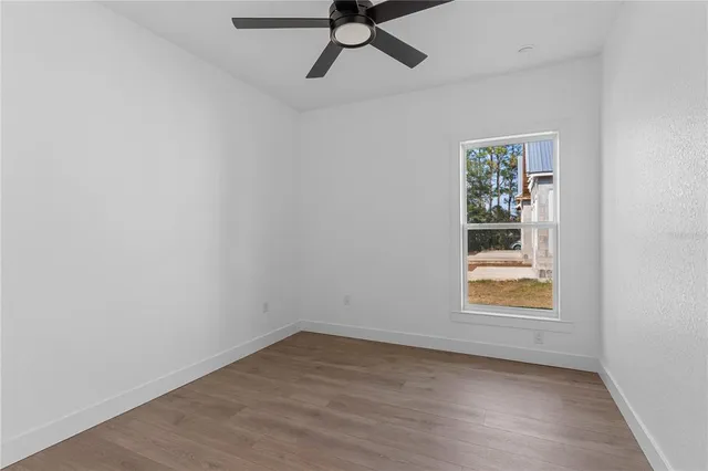an empty room with a window and ceiling fan