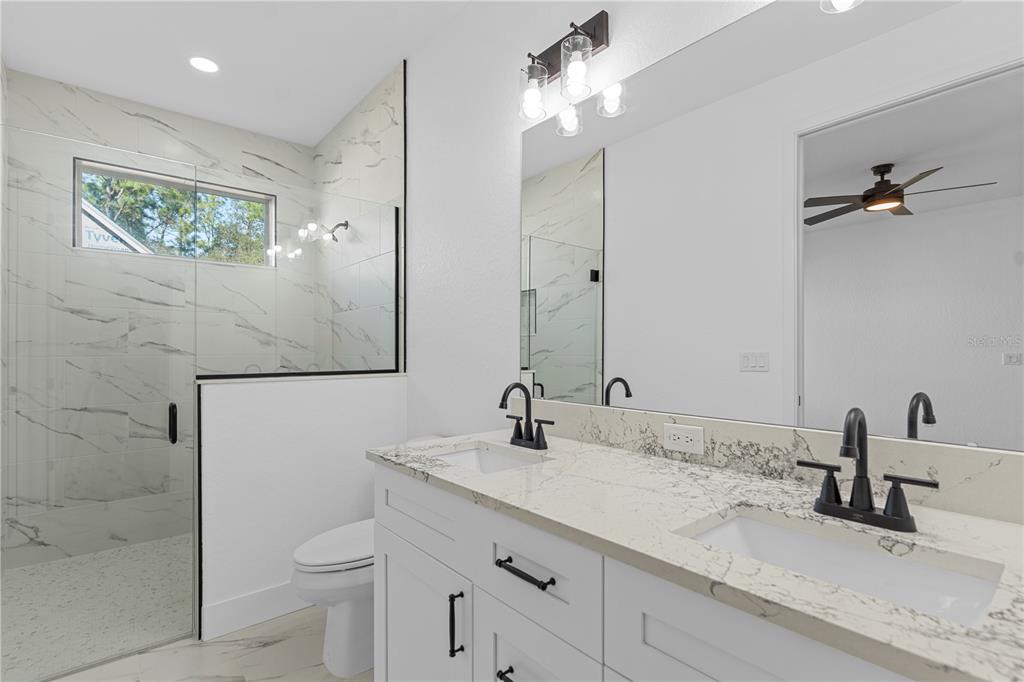 8090 Nordica Road Brooksville, FL 34613 - Photo 44 of 56 a bathroom with a granite countertop sink a toilet and a mirror