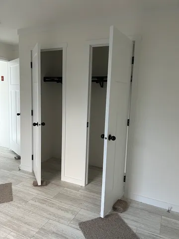 an empty room with wooden floor and a hallway