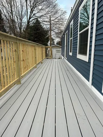 a view of balcony with wooden floor and fence and a floor to ceiling window