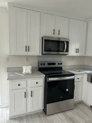 a kitchen with stainless steel appliances granite countertop grey cabinets a stove a sink and dishwasher