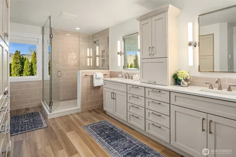 a spacious bathroom with a double vanity sink a large mirror a bathtub and next to a window