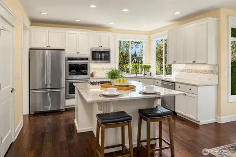 a kitchen with a refrigerator a stove a sink and white cabinets with wooden floor